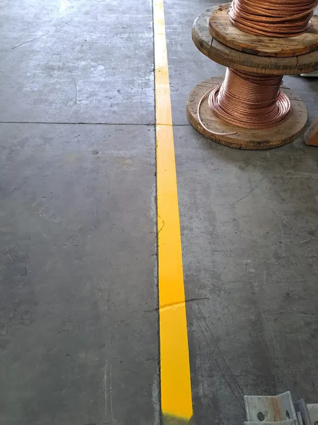 Zonas de carga y descarga delimitadas para mejorar la seguridad operativa. Descripción: Imagen que muestra la delimitación precisa de áreas de carga, aplicando colores reglamentarios para prevenir accidentes y optimizar la circulación en la bodega. Zonas de carga delimitadas con pintura amarilla y negra