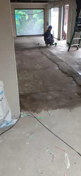 Etapa previa de revisión y nivelación del piso antes de la instalación de cerámica, parte clave para evitar fallas y sobrecostos. Trabajador revisando y nivelando el piso antes de instalar cerámica en obra.