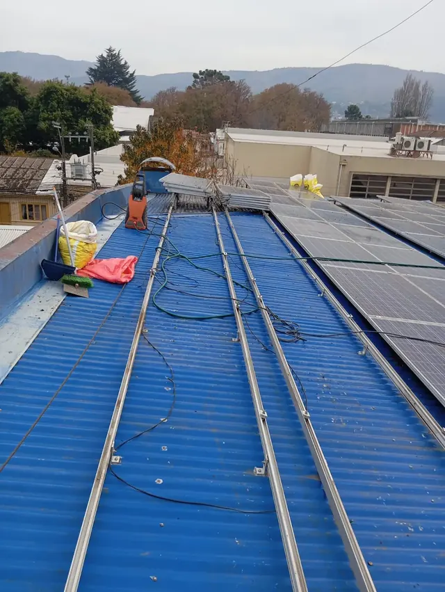 Limpieza avanzada de techumbre industrial con paneles solares, asegurando durabilidad y eficiencia. Cubierta azul con herramientas y materiales de limpieza industrial.