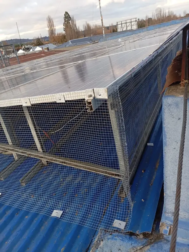 Resultado final del mantenimiento con instalación de malla para protección de paneles y canaletas. Cubierta azul con malla protectora tras limpieza y mantenimiento preventivo.