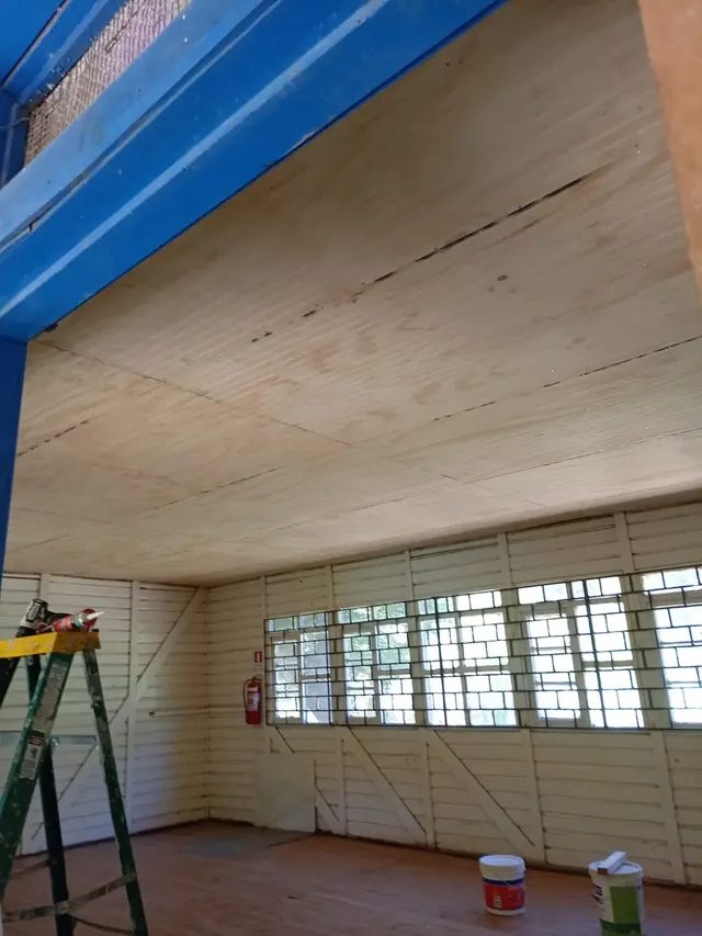 Colocación de cielo de terciado ranurado durante el proyecto de mejora de la Escuela Bellavista, Quilaco. Cielo ranurado nuevo en proceso de instalación en aula escolar rural.