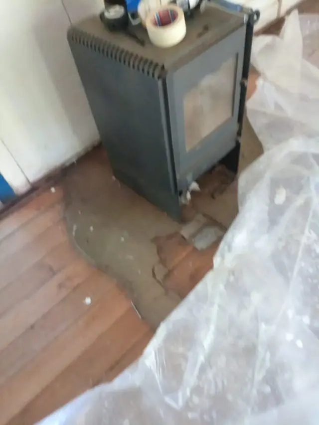 Instalación y mejora del sistema de calefacción con estufa a combustión lenta en Escuela Bellavista, Quilaco. Instalación de calefactor sobre base protectora en aula de escuela rural.