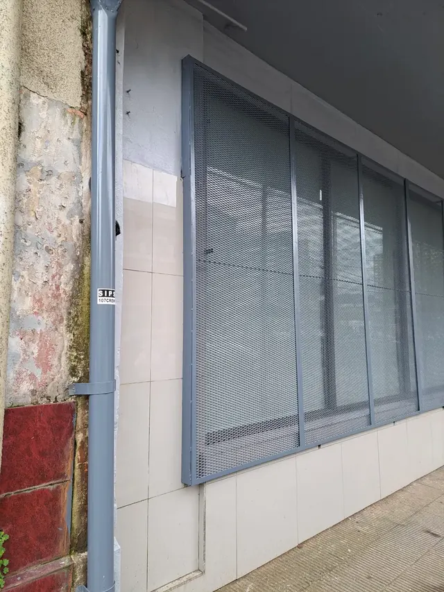 Instalación de paneles metálicos de seguridad. Operarios instalando placas metálicas protectoras en fachada de sucursal Frontel Temuco.