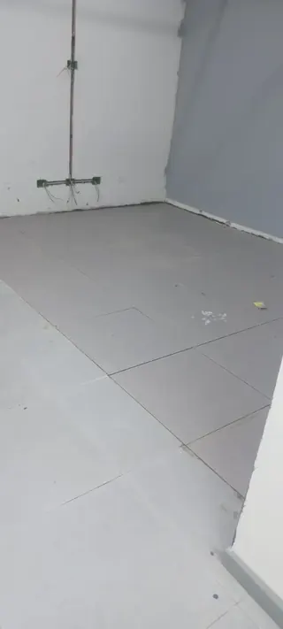 Conectividad estratégica: cada punto de datos y energía se instala según el plano técnico de la sala. Esquina de una sala con cajas de derivación eléctrica y cables expuestos en el muro, sobre un piso de concreto nivelado para pavimentos.