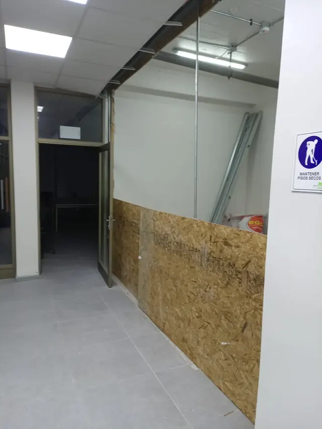 Configuración de los nuevos límites espaciales utilizando materiales de alta resistencia. Instalación de paneles de madera OSB como base para nuevos tabiques en un pasillo con piso de porcelanato ya instalado.
