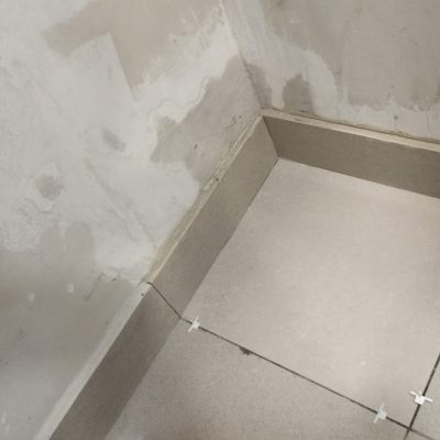 Proceso de instalación de porcelanato tras reparación por filtración de agua.