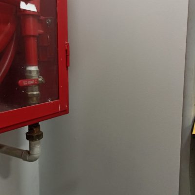 Muro recién reparado junto al gabinete de red húmeda en farmacia Cruz Verde.