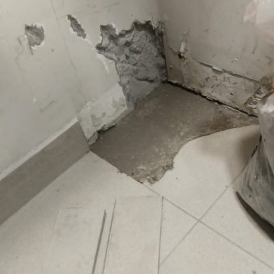 Área de muro y piso deteriorada por humedad antes de la reparación.