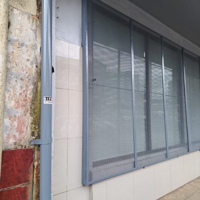 Operarios instalando placas metálicas protectoras en fachada de sucursal Frontel Temuco.