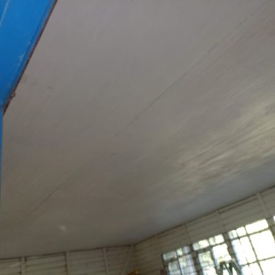 Cielo pintado y terminaciones interiores en aula de escuela rural.