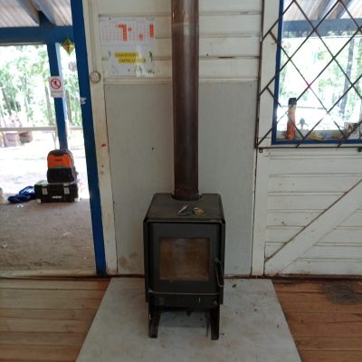 Estufa instalada en aula con base de hormigón para seguridad y confort térmico.