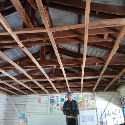 Trabajador reforzando estructura de techumbre durante el proceso de mejora en escuela rural.