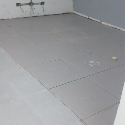 Esquina de una sala con cajas de derivación eléctrica y cables expuestos en el muro, sobre un piso de concreto nivelado para pavimentos.