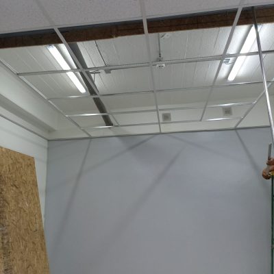 Estructura de perfilería blanca para cielo americano con tubos LED de luz blanca instalados y algunas palmetas acústicas colocadas.