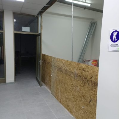 Instalación de paneles de madera OSB como base para nuevos tabiques en un pasillo con piso de porcelanato ya instalado.